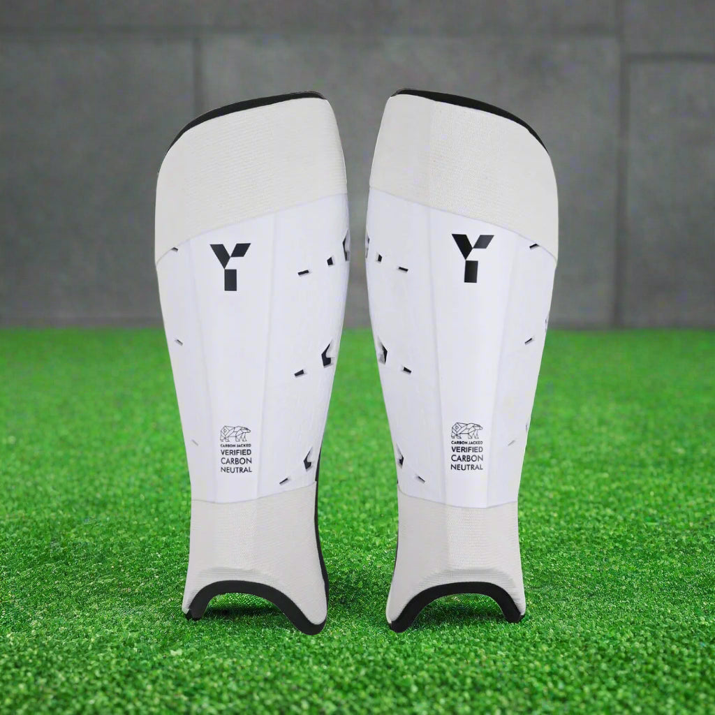 A pair of white Y1 shin pads with spine reinforcement and a removable hygiene lining.