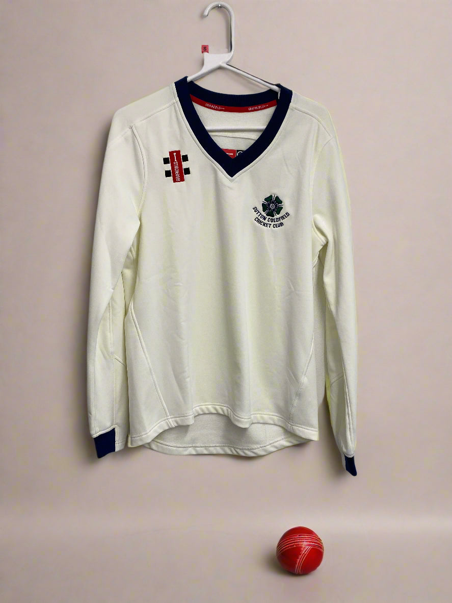 A junior's long-sleeved white cricket sweater with navy trims and an embroidered badge on the chest, displayed on a hanger.