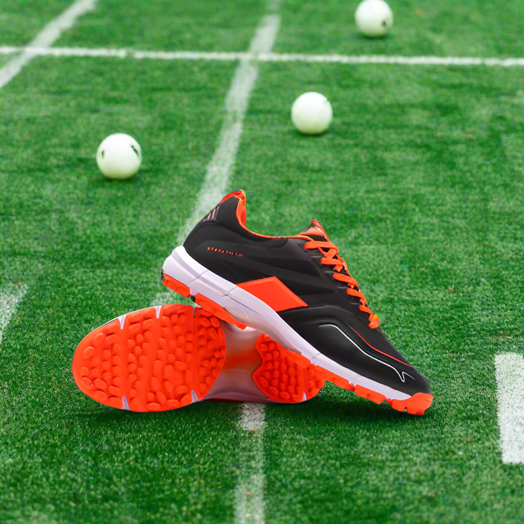 A pair of Grays Stealth 1.0 Senior Astro hockey shoes with a high-performance rubber outsole, predominantly black with orange accents.