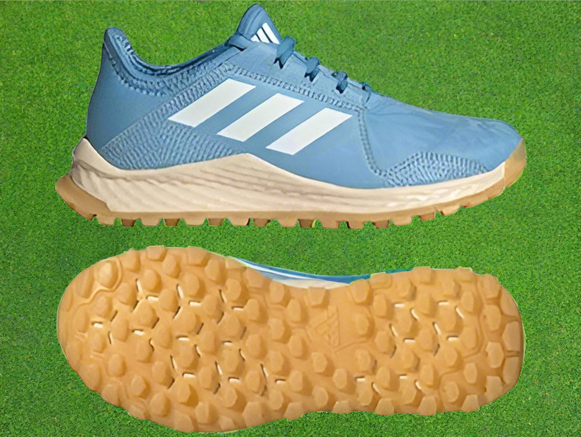 A pair of blue junior hockey shoes with white stripes, showcasing the sole with multi-directional studs.