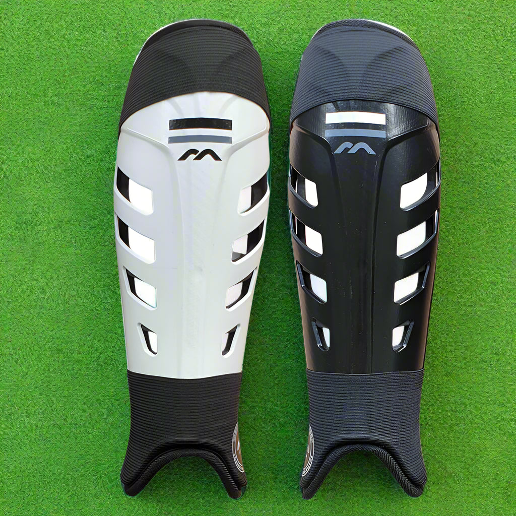 A pair of shinguards for hockey goalkeeping, available in white with black trim and black with white trim. Both have a plastic shell and a raised shin 'spine' design.