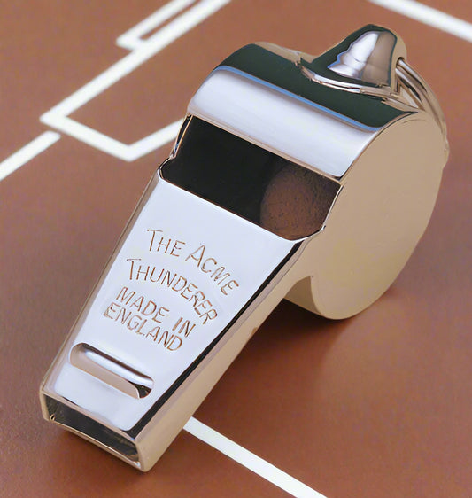 A silver-colored, brass whistle with a tapered mouthpiece and the text 'THE ACME THUNDERER MADE IN ENGLAND' engraved on it.