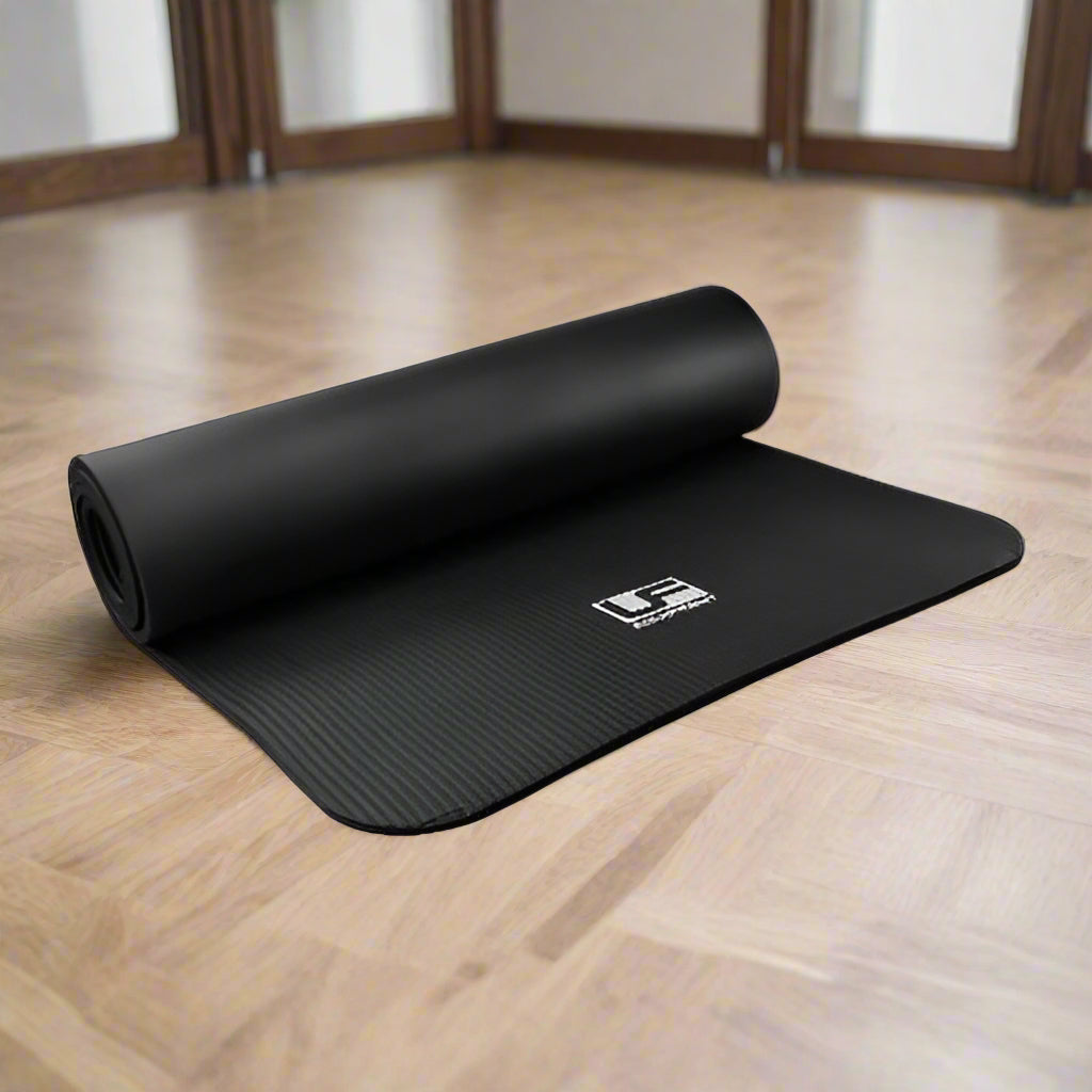 A rolled up black yoga or pilates mat with a textured surface, featuring a logo on the bottom corner.