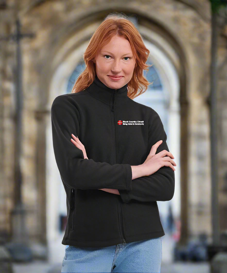 Person wearing a black jacket with a logo on a white background