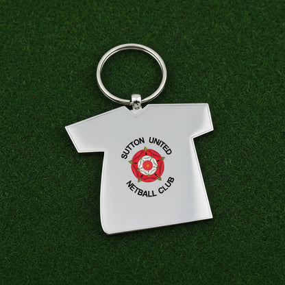 A white t-shirt graphic with a black outline, featuring the Sutton United Netball Club logo in the center. The logo includes a red rose with a white center and green leaves, surrounded by the text 'SUTTON UNITED NETBALL CLUB' in black.
